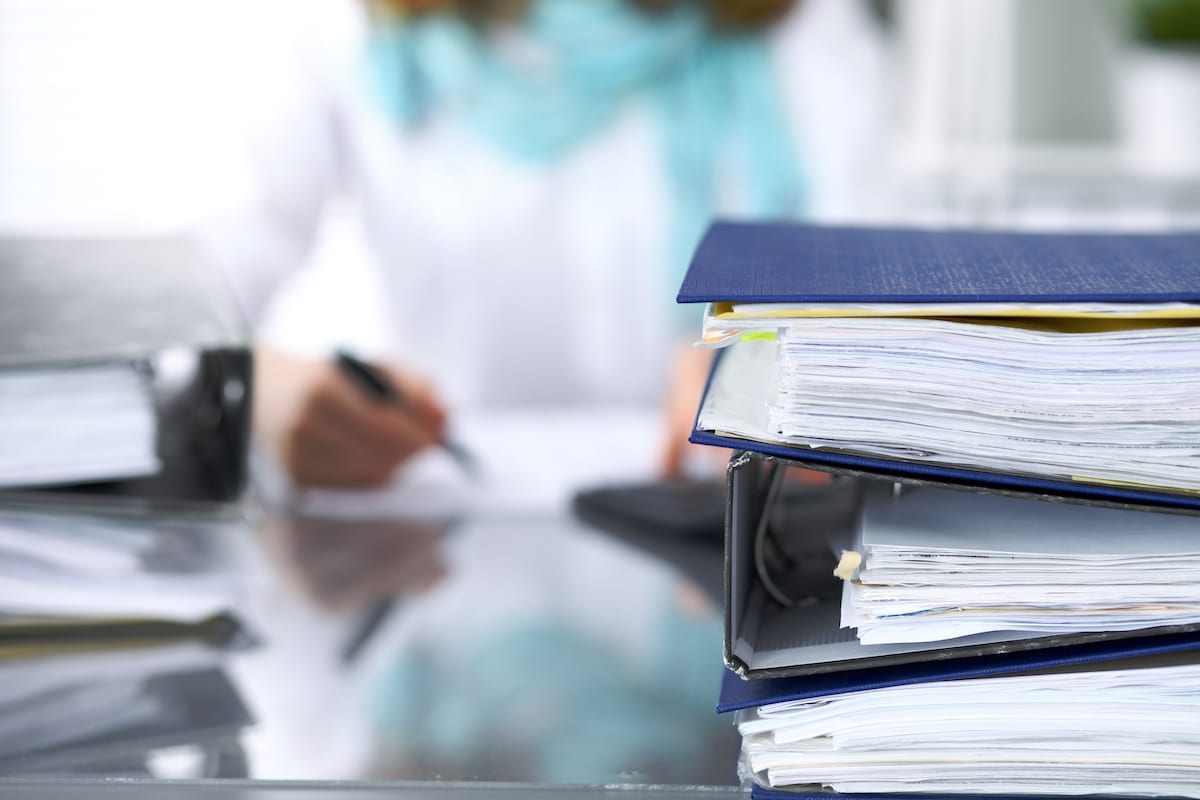 Binders with papers are waiting to be processed with businesswoman or secretary back in blur. Internal Revenue Service inspector checking financial document